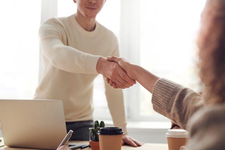 Man shakes hand with a woman across an office desk