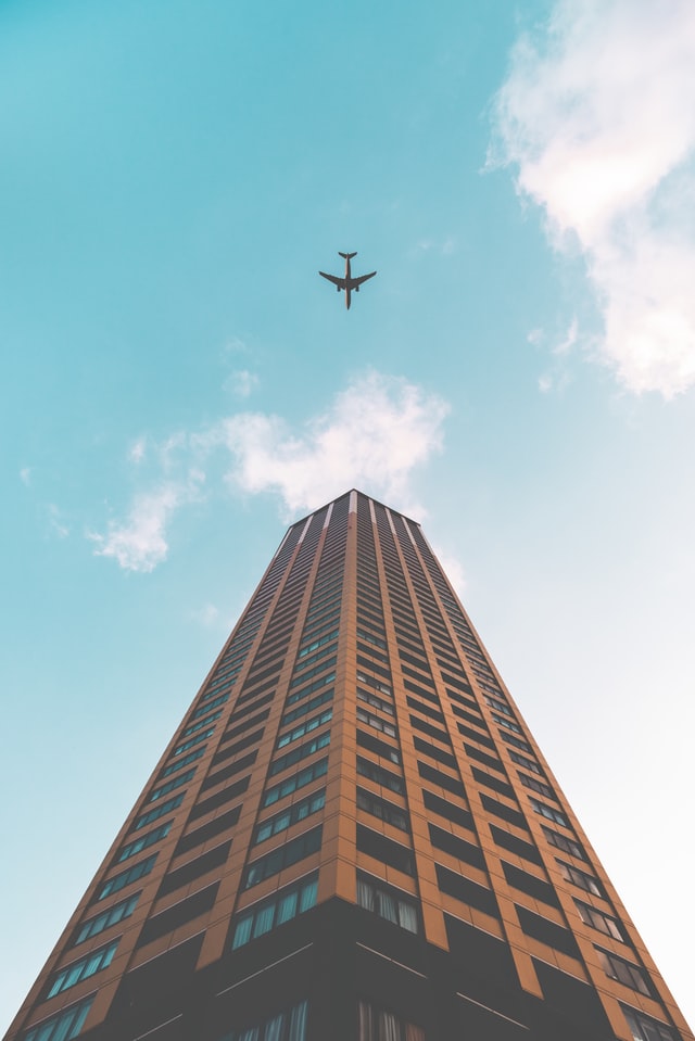 Airplane flying above tall building