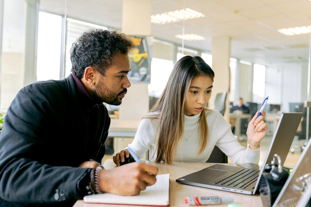 Man and Woman Sitting at Table looking at a laptop screen