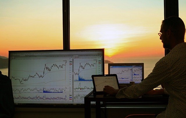 Man looking at stockcharts on computer screens