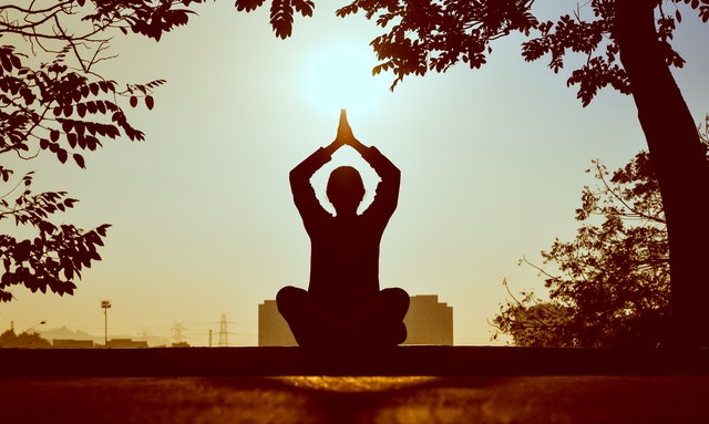 Silhouette of Man doing yoga, facing the city