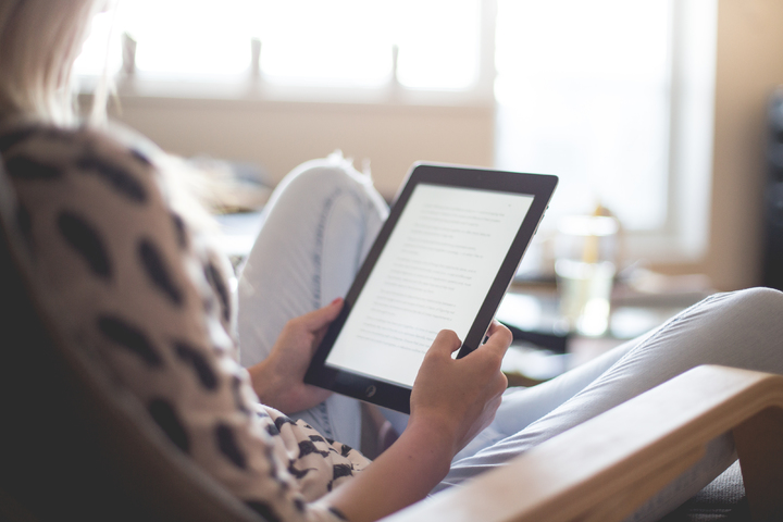 a person confortably reading a tablet