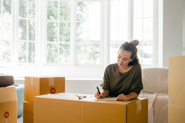 Woman signing box near large window in sunlight at home