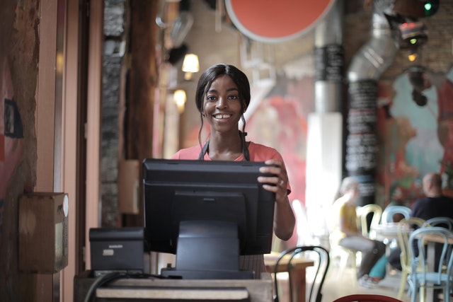 Cheerful black waitress standing at counter