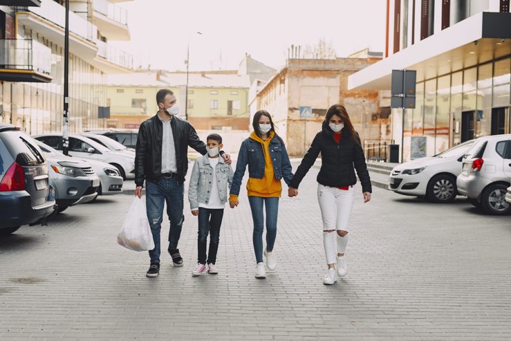 Family of four walking down the street with Covid masks on