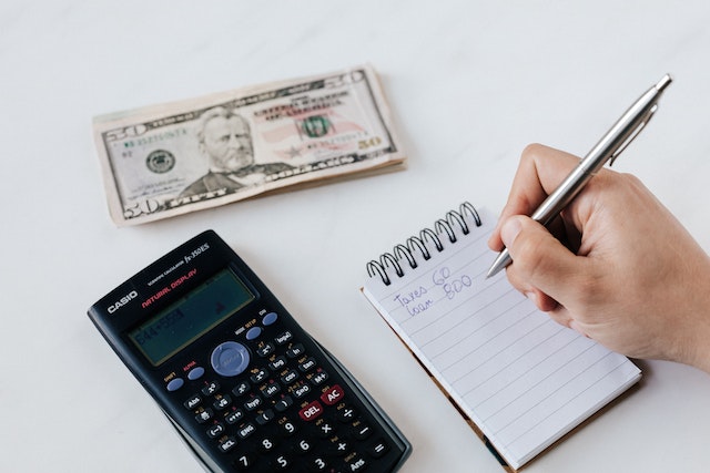 Financial calculator, note pad and American currency.