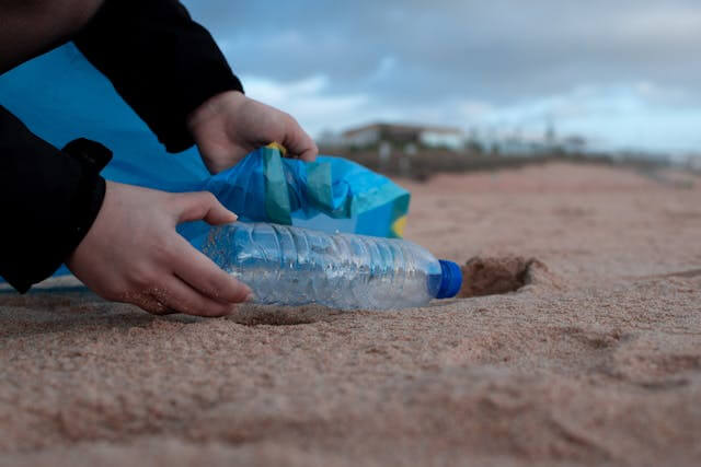 A person picking up garbage from the beach